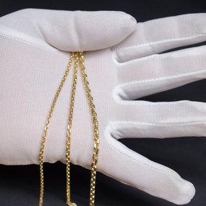 May include: Three gold chains of different widths, laid out on a white surface.