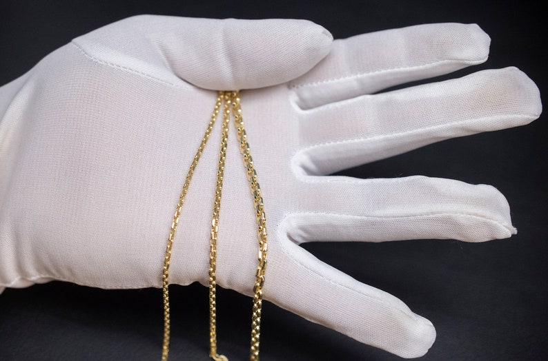 May include: Three gold chains of different widths, laid out on a white surface.