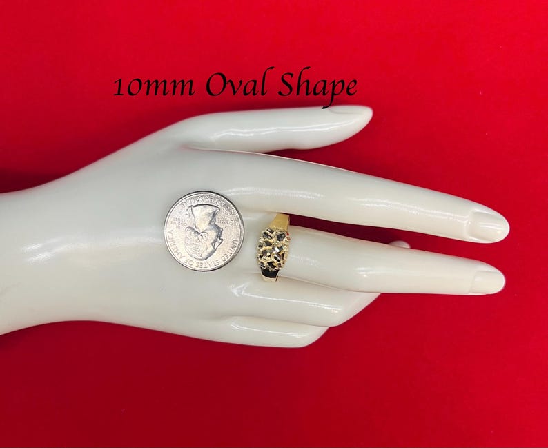 May include: A gold ring with a 10mm oval-shaped stone. The ring is on a hand, and a US quarter is shown for size comparison. 10mm Oval Shape.