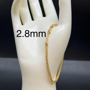 May include: A gold chain bracelet with a 2.8mm width. The bracelet is displayed on a white mannequin hand.