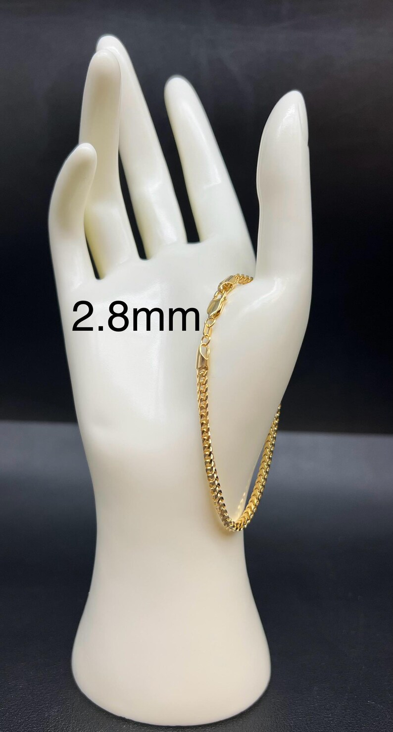 May include: A gold chain bracelet with a 2.8mm width. The bracelet is displayed on a white mannequin hand.