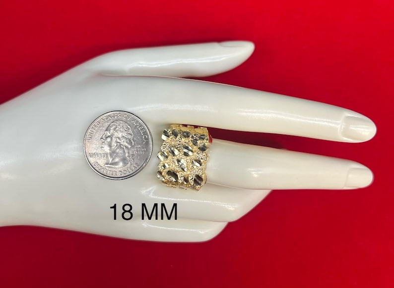 May include: A gold ring with a textured design. The ring is 18 mm wide. The ring is displayed on a hand.