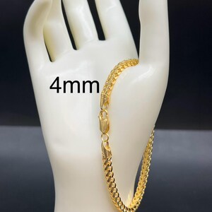 May include: A gold chain bracelet with a 4mm width. The bracelet is on a white mannequin hand.