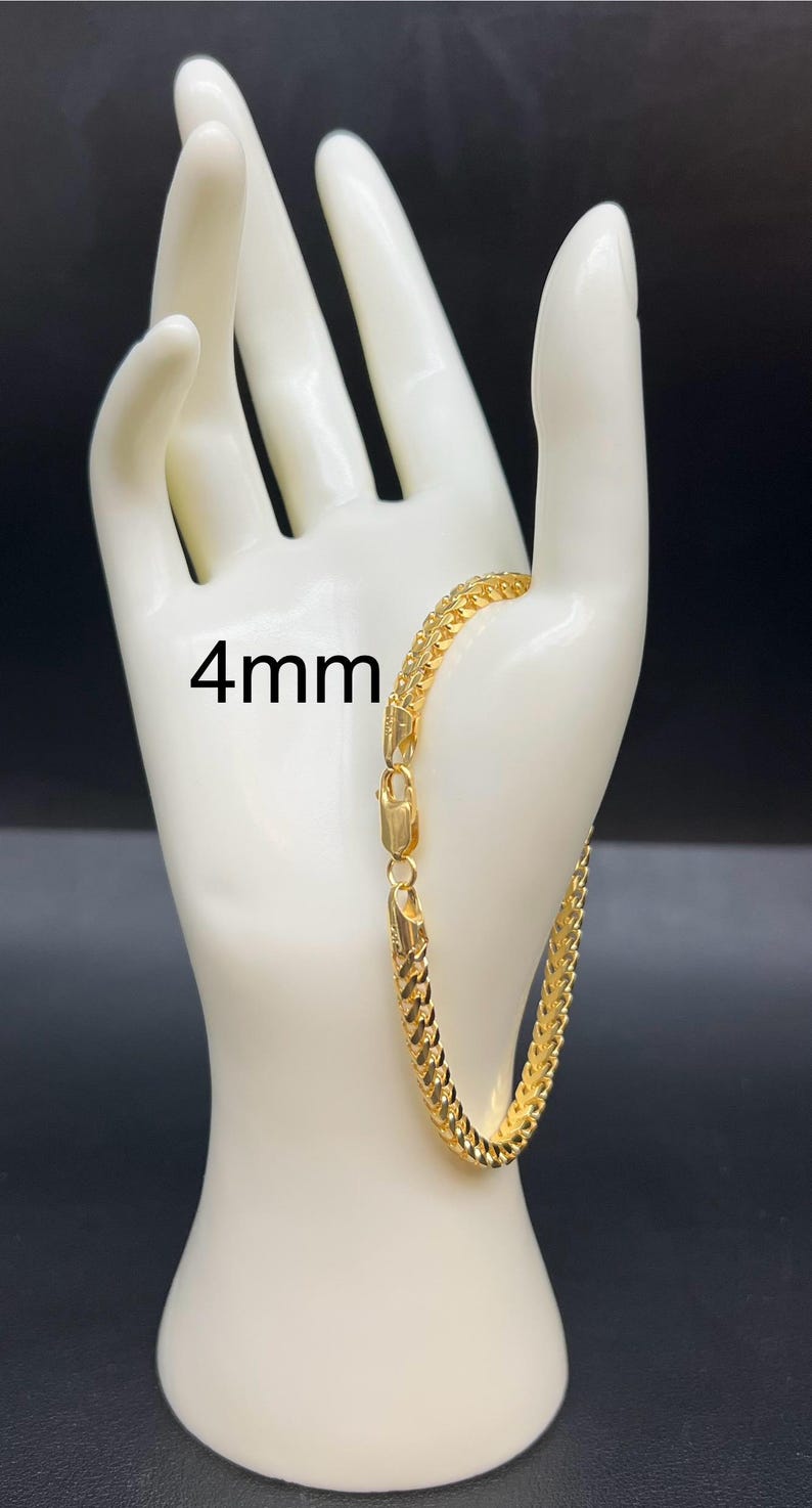 May include: A gold chain bracelet with a 4mm width. The bracelet is on a white mannequin hand.