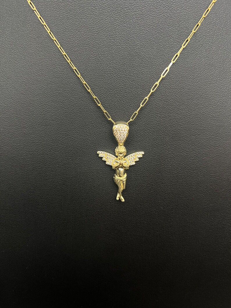 Puede incluir: Collar de cadena de oro con un peque&ntilde;o colgante de &aacute;ngel detallado incrustado con piedras de circonita c&uacute;bica transparentes.