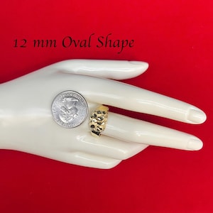 May include: A gold ring with a textured oval shape. The ring is 12 mm in size and is shown on a mannequin hand.