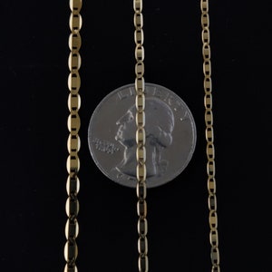 May include: Three gold chains of different lengths, laid out against a black background. A US quarter is placed between the two longer chains for scale.