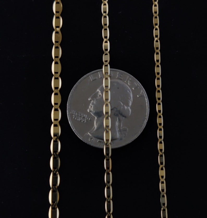 May include: Three gold chains of different lengths, laid out against a black background. A US quarter is placed between the two longer chains for scale.