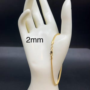 May include: A gold chain bracelet with a lobster clasp. The chain is 2mm wide.