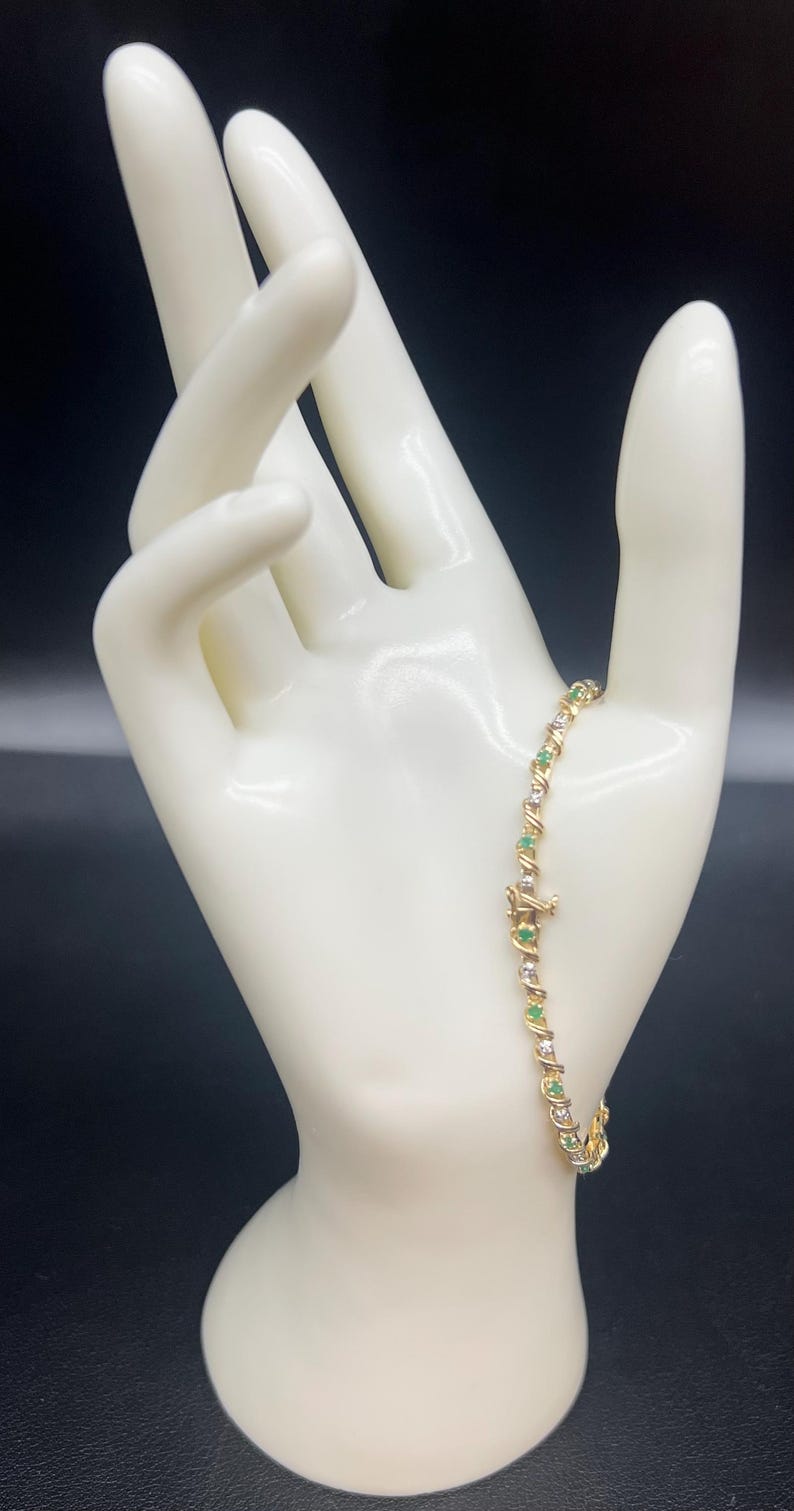 May include: A gold bracelet with alternating emerald green and clear round stones.