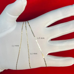 May include: Three gold chains of different widths laid out on a white surface. The chains are labeled with their widths in millimeters: 1.3 mm, 1.5 mm, and 1.8 mm.