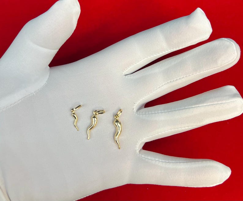 May include: Three gold-coloured pepper charm pendants of varying sizes. The charms are shaped like a pepper and are displayed on a white surface.