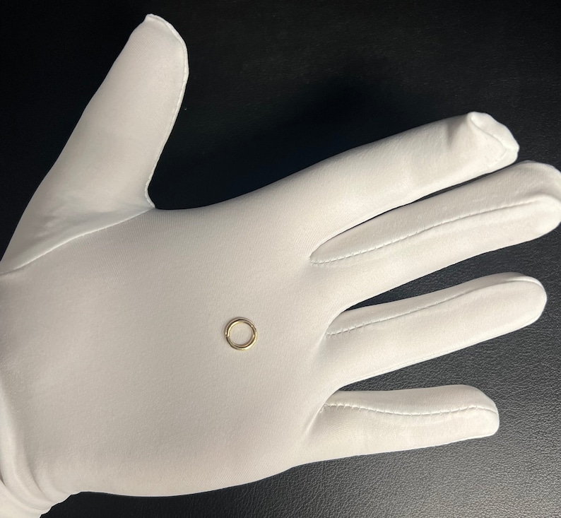 May include: A small, gold-colored hoop earring on a white surface.