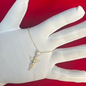 Puede incluir: Un collar de cadena de oro con un peque&ntilde;o colgante de &aacute;ngel incrustado con cristales transparentes.