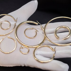May include: A set of six gold hoop earrings of varying sizes. The earrings are displayed on a white surface.