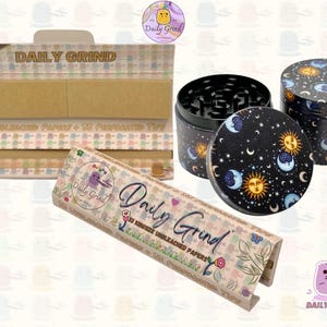 A light brown and beige box with the text 'Daily Grind' and ‘Kingsize Unbleached Papers' on it. The box is open and there are brown papers inside. There is a tobacco grinder with a cartoon sun and moon astrology design on it next to the box and The 'Daily Grind' logo is in the corner of the image
