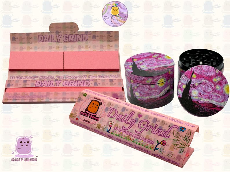 A pink and white box with the text 'Daily Grind' and ‘Kingsize Pink Papers' on it. The box is open and there are Pink papers inside. There is a tobacco grinder next to the box with a pink night sky art design and The 'Daily Grind' logo is in the corner of the image