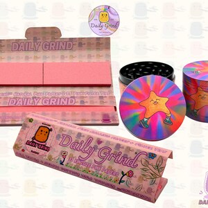 A pink and white box with the text 'Daily Grind' and ‘Kingsize Pink Papers' on it. The box is open and there are Pink papers inside. There is a tobacco grinder with a very happy and confident star character in the middle with rays of light behind him next to the box and The 'Daily Grind' logo is in the corner of the image