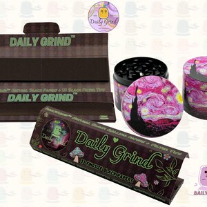 A black and green box with the text 'Daily Grind' and Kingsize Black Papers' on it. The box is open and there are black papers inside. There is a tobacco grinder next to the box with a pink star night design on it and the 'Daily Grind' logo is in the corner of the image