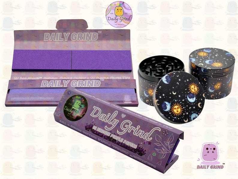 A dark Purple packet and a Green box with the text 'Daily Grind' on both and ‘Kingsize Purple Papers' on one and ‘Kingsize Green Papers’ on the other. Both boxes open showing green papers in one and purple in the other. There is a tobacco grinder with a cartoon sun and moon astrology design on it underneath it and The 'Daily Grind' logo is in the corner of the image