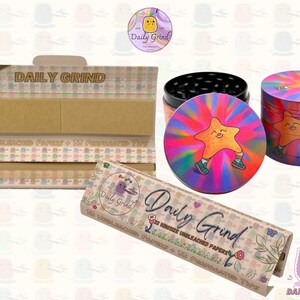A light brown and beige box with the text 'Daily Grind' and ‘Kingsize Unbleached Papers' on it. The box is open and there are brown papers inside. There is a tobacco grinder with a very happy and confident star character in the middle with rays of light behind him next to the box and The 'Daily Grind' logo is in the corner of the image