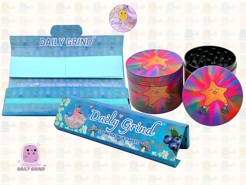A deep blue and light blue box with the text 'Daily Grind' and ‘Kingsize Blue Papers' on it. The box is open and there are blue papers inside. There is a tobacco grinder with a very happy and confident star character in the middle with rays of light behind him next to the box and The 'Daily Grind' logo is in the corner of the image