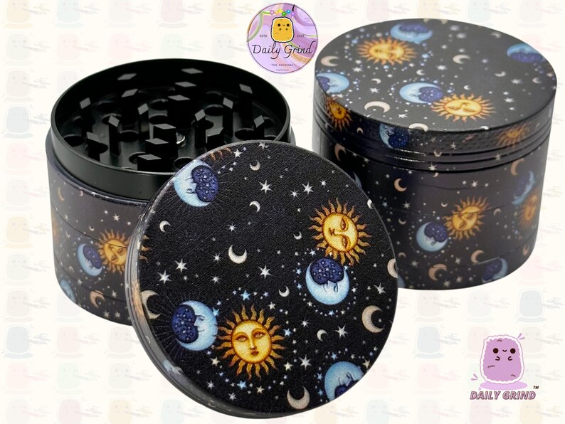 A four piece Metal Tobacco Grinder with a spiritual astrology design. The grinder features a cartoon sun & moon in a dark night sky full of stars . The inside of the grinder is black. The Daily Grind logo is visible in the corner of the image