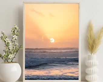 Könnte beinhalten: Ein gerahmtes Foto eines Sonnenuntergangs über dem Meer. Die Sonne geht hinter dem Horizont unter und wirft einen warmen orangenen Schein auf das Wasser. Die Wellen brechen an der Küste und erzeugen ein Gefühl von Frieden und Ruhe.