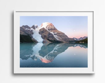 Puede incluir: Fotografía enmarcada de un paisaje montañoso reflejado en un lago en calma. La montaña tiene una cima nevada y un glaciar. El cielo transita del rosa al azul, y se ve la luna. El agua es de color azul claro.