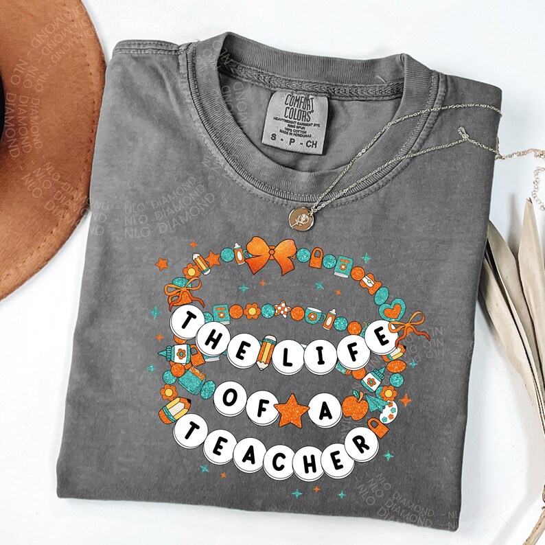 pepper Comfort Colors® shirt with colorful beaded bracelet design spelling "The Life Of A Teacher", surrounded by school-themed icons