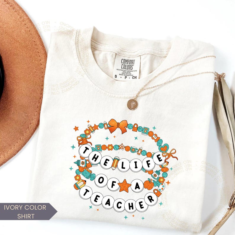 ivory Comfort Colors® shirt with colorful beaded bracelet design spelling "The Life Of A Teacher", surrounded by school-themed icons