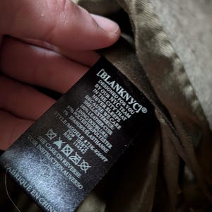 May include: A black label with white text from Blank NYC, with the text "DESIGNED FOR YOU BY OUR NYC TEAM IN THE CITY THAT NEVER SLEEPS BECAUSE WE CARE". The label also includes fabric composition and care instructions.