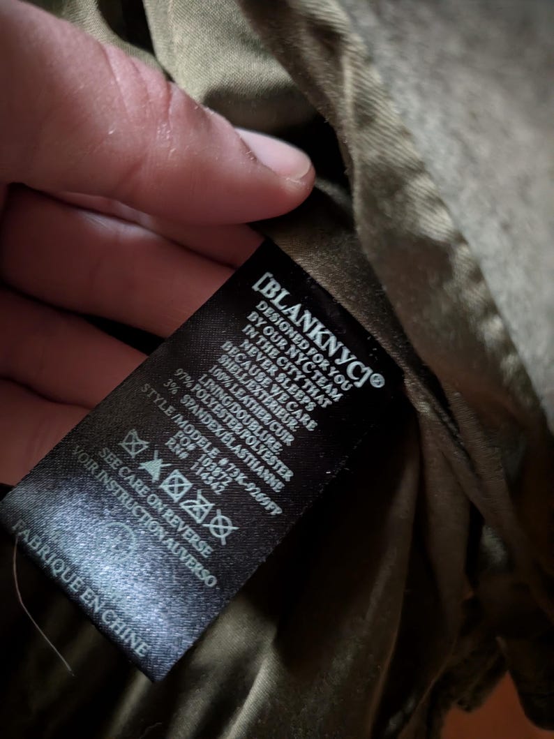 May include: A black label with white text from Blank NYC, with the text "DESIGNED FOR YOU BY OUR NYC TEAM IN THE CITY THAT NEVER SLEEPS BECAUSE WE CARE". The label also includes fabric composition and care instructions.