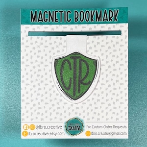 May include: A magnetic bookmark with a shield design. The shield is green with the letters "CTR" in black. The bookmark is attached to a white card with the words "MAGNETIC BOOKMARK" at the top. The card has a dotted pattern.