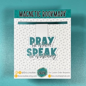 May include: Teal blue magnetic bookmark with the text "PRAY He is there SPEAK He is listening". The bookmark is on a white background with a gray polka dot pattern.