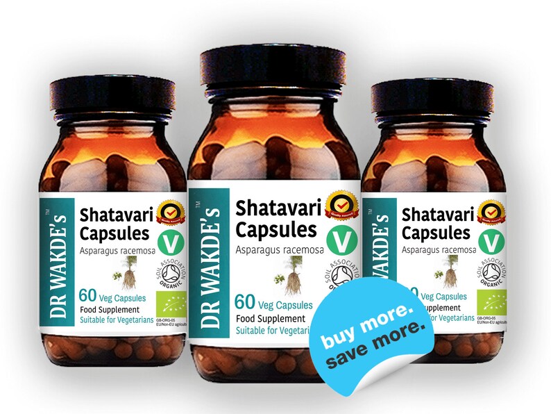 May include: Three brown glass bottles with white labels containing Shatavari Capsules, a food supplement made with Asparagus racemosa. The labels feature a green leaf and a green circle with the text "Soil Association Organic". The bottles are arranged in a row with a blue sticker on the front of the middle bottle that says "buy more. save more."