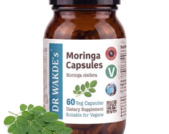 May include: A brown glass bottle containing Dr. Wakde's Moringa Capsules, a dietary supplement. The white label features the text Moringa Capsules, Moringa oleifera, 60 Veg Capsules, and a green V symbol. Fresh green moringa leaves are in front.