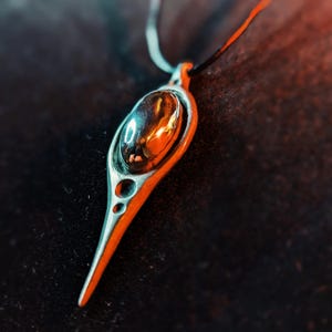 Peut inclure: Un collier avec un pendentif en argent de forme larme. Le pendentif a une surface lisse et polie et une petite ouverture ronde en haut. Le pendentif est attaché à une chaîne en argent.