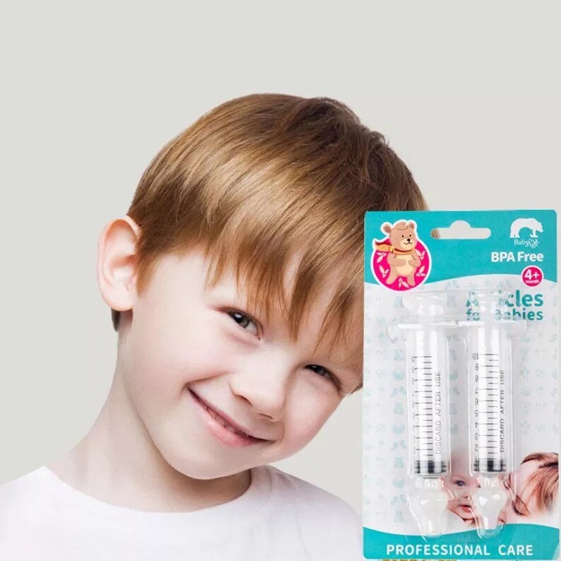 K&ouml;nnte beinhalten: Zwei transparente Plastikspritzen mit einem blauen und wei&szlig;en Etikett mit der Aufschrift "BPA Free 4+ Needles for Babies Professional Care". Das Etikett zeigt auch einen Comic-B&auml;ren, der einen roten Umhang tr&auml;gt.