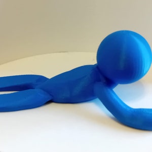 May include: A blue 3D printed doorstop shaped like a person lying on their stomach with their arms outstretched.