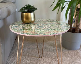 May include: A round side table with a floral patterned top and gold hairpin legs. A small potted succulent sits on the table.