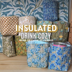 Può includere: Una collezione di custodie termiche per bevande con vari motivi floreali e geometrici. I colori includono blu, verde, beige e bianco. Il testo "INSULATED DRINK COZY" e "MORE OPTIONS AVAILABLE" è visibile.