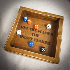May include: A wooden box with the words "Get the Flamer The Heavy Flamer" engraved on the inside. There are six dice inside the box, two blue, one orange, and three white.