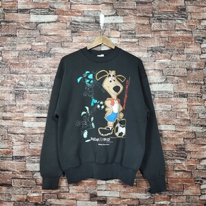Puede incluir: Sudadera negra con un estampado gráfico de un perro de dibujos animados que lleva un uniforme de fútbol y sostiene un balón de fútbol. El texto "World Cup USA 94" está impreso en la sudadera.