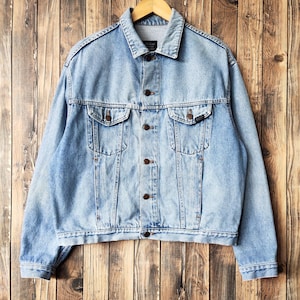 May include: A light blue denim jacket with a button closure and two front pockets. The jacket has a faded look and is made of a soft, comfortable material.