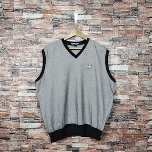 Puede incluir: Un chaleco sin mangas de punto gingham blanco y negro con cuello en V negro y un pequeño logotipo bordado en el pecho. El texto "POLO GOLF" es visible en la etiqueta.