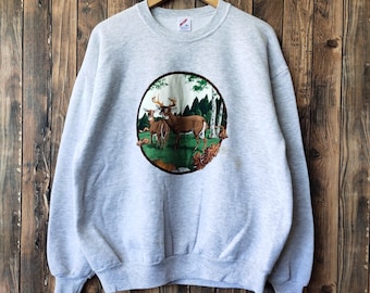 May include: Gray sweatshirt with a circular graphic of a deer family in a forest setting.