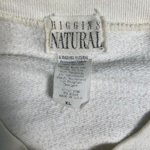 May include: White cotton sweatshirt with a white tag that reads "Higgins Natural" and "A Higgins Natural" with care instructions and size XL.