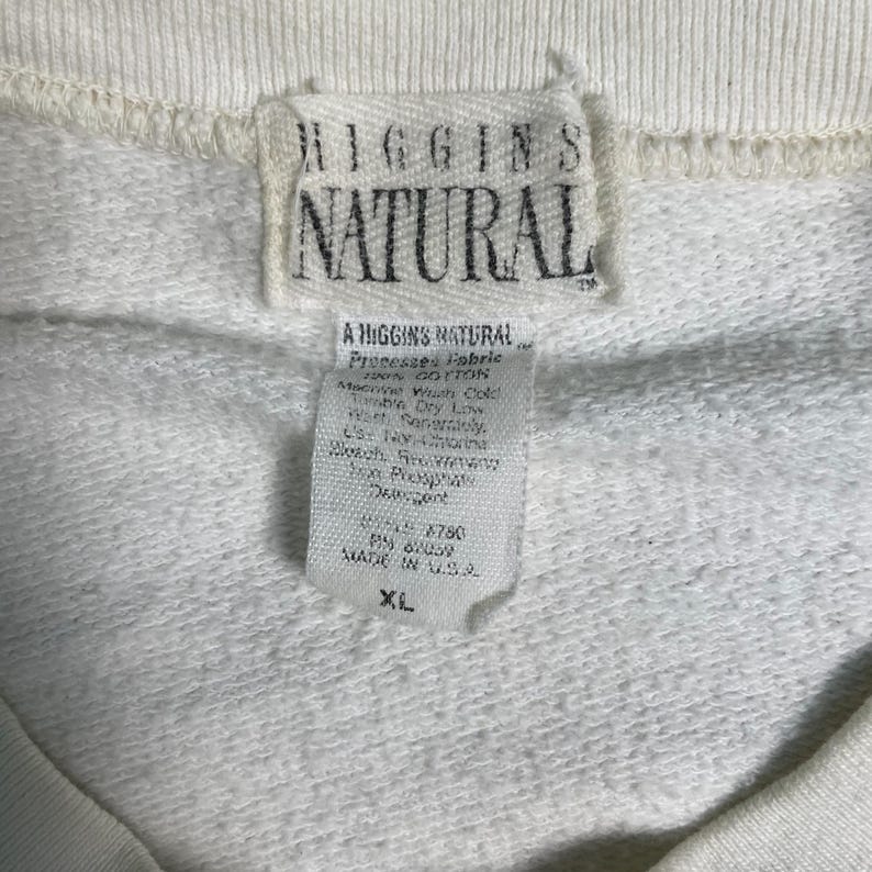 May include: White cotton sweatshirt with a white tag that reads "Higgins Natural" and "A Higgins Natural" with care instructions and size XL.