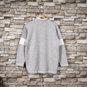 May include: A gray and white striped sweater with a long sleeve and a crew neck.